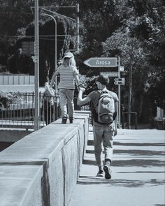 two people walking across a bridge with backpacks on their back and one person holding the other hand