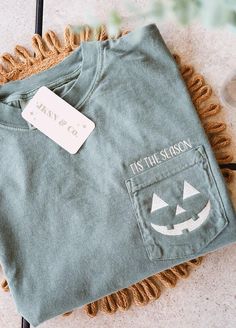 Celebrate spooky season in style with this embroidered Jack-o'-Lantern pocket tee! Perfect for Halloween lovers, this tee features a cheerful Jack-o'-lantern embroidered on the pocket, with the words "Tis the Season" stitched just above it. Made on a premium Comfort Colors T-shirt, this is the ultimate combination of cozy comfort and festive flair! 🎃 Design:     A cute Jack-o'-lantern embroidered directly on the pocket     The phrase "Tis the Season" is beautifully stitched above the pocket, ad Minimalist Holiday Shirt, Halloween Pocket Tee, Embroidered Pocket Tees, Long Sleeve Shirt Design, Cricut Projects Clothes, Halloween Cricut Shirts, Embroidery Shirt Designs, Pocket Tee Designs, Flair Design