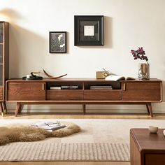 a living room filled with furniture next to a wall mounted book shelf and lamp on top of a rug