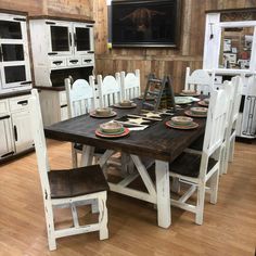 a kitchen table with chairs and plates on it in front of a wall mounted oven