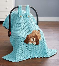 a crocheted teddy bear blanket sitting on top of a wooden floor next to a chair