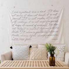 a couch with pillows and vases on it in front of a large wall hanging