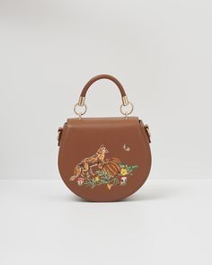 Key Features:


  
Charming Autumn Embroidery: Features a detailed fox and pumpkin design, surrounded by mushrooms, a moth, and winding vines, bringing the essence of fall to your accessory collection.

  
Premium Vegan-Friendly Faux Leather: Crafted from high-quality polyurethane in a rich tan shade, offering both style and sustainability.

  
Versatile Carrying Options: Includes a sturdy top handle and an adjustable cross-body strap for convenient, adaptable use.

  
Secure Magnetic Fastening: Fox Pumpkin, Saddle Purse, Autumn Embroidery, Pumpkin Design, Saddle Bag, Vegan Friendly, Body Bag, Saddle Bags, Moth