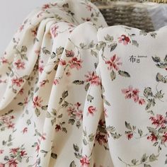 the fabric is white with red flowers and green leaves on it, along with a wicker basket