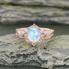 an opal and diamond ring sitting on top of a rock