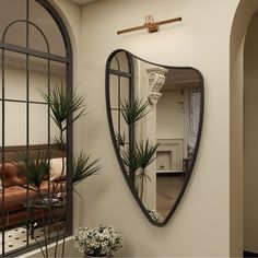 a mirror hanging on the side of a wall next to a couch and potted plant