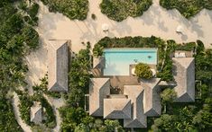 an aerial view of a house surrounded by trees and bushes with a pool in the middle