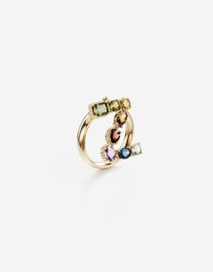 The line is completed by matching rings, characterized by a refined rounded yellow gold band with engraved logo and a pendant letter enriched by a veritable rainbow of natural gemstones such as topaz, garnet, amethyst, citrine, peridot and tourmaline. the shades of their colours, dominated by blue, green, purple, red, pink and yellow, evoke the warm atmospheres of Sicily. The multiple shapes of the crystals are also emphasized by the bezels, which alternate twisted thread processing and smooth surfaces. Technical specifications. Gold 18 Kt Gemstones. 1 square cushion light blue “Sky” topaz, 1 oval blue “London” topaz, 1 oval light purple amethyst, 1 oval orangish red hessonite garnet, 1 pear orange “Madera” quartz, 1 round light yellow citrine, 1 square cushion yellowish green peridot, 1 r Luxury Yellow Gold Rings With Gemstones, Luxury Sterling Silver Yellow Gold Rings, Luxury Multicolor Sterling Silver Rings, Elegant Multicolor Stackable Jewelry, Multicolor 14k Gold Hallmarked Rings, Multicolor 14k Gold Rings, Hallmarked Multicolor 14k Gold Rings, Luxury 14k Gold Multicolor Jewelry, Luxury Multicolor Ring Jewelry