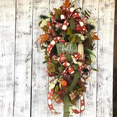 a fall wreath hanging on the side of a wooden fence