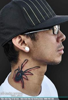 a man with a spider tattoo on his neck and behind his ear, wearing a baseball cap