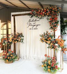 an arrangement of flowers on display in front of a white backdrop for a wedding ceremony