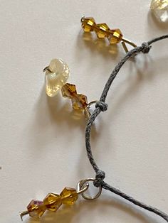 This fashionable delicate bracelet handcrafted with earthy gray thread knots, citrine gemstones and amber glass beads is a bright rustic addition. Citrine gemstones in pale yellow tones add elegance to the subtle glimmer of amber bicone faceted crystal glass beads. Adjust length of the bracelet with included jump rings. Gemstone - Citrine Beads - Bicone faceted crystal glass beads Color - Pale yellow, amber Bracelet closure - Lobster claw Other materials - Gray beading thread, metal jewelry pins Thread Knots, Rings Gemstone, Beading Thread, Citrine Beads, Amber Bracelet, Jewelry Pins, Yellow Tones, Citrine Gemstone, Faceted Crystal