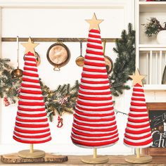 three red and white christmas trees sitting on top of a wooden table next to a clock