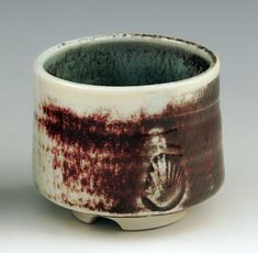 a close up of a cup on a white surface with red and black streaks around it