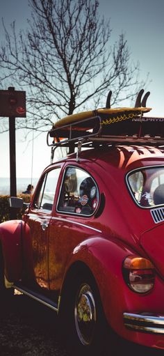 a red car with a surfboard on the top of it's roof rack