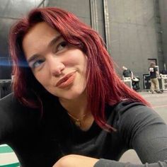 a woman with red hair and blue eyes sitting at a table in front of a building