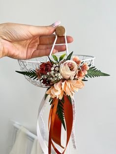 a person holding a flower arrangement in their hand