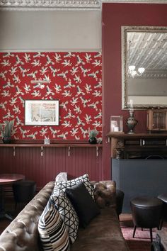 a living room filled with furniture and a red wallpaper covered in bird designs on the walls