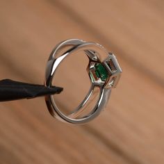 It is a lab emerald ring. The main stone is 7mm*7mm round cut, weight about 1.3 carats. The basic metal is sterling silver and plated with rhodium. To change the metal to a solid gold (white/rose) or platinum is also available, please ask for a quotation if you want. You can also go to my shop Home for more elegant rings: https://www.etsy.com/shop/godjewelry?ref=hdr_shop_menu More lab emerald rings: https://www.etsy.com/shop/godjewelry?ref=seller-platform-mcnav&section_id=20709240 Customizat 14k White Gold Emerald Cut Halo Ring, Emerald Cut Gemstone Halo Ring In White Gold, Emerald Cut Diamond Birthstone Ring With Halo Setting, Elegant Emerald Solitaire Ring With Round Band, Elegant Solitaire Emerald Ring With Round Band, Round Cut Emerald Diamond Ring, Silver Emerald Solitaire Ring In 14k White Gold, Fine Jewelry Emerald Solitaire Ring In Round Cut, Emerald Ring With Prong Setting In Round Cut