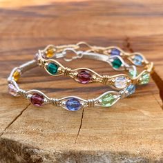 two bracelets with different colored stones sitting on top of a piece of wood