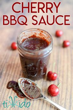 cherry bbq sauce in a jar with spoon on the side and cherries around it