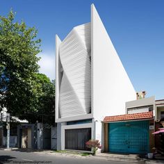 a large white building sitting on the side of a road next to a tall tree