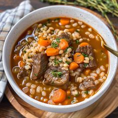 a white bowl filled with stew and carrots on top of a wooden cutting board