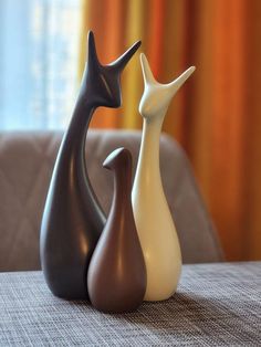 two vases sitting on top of a table in front of a curtained window