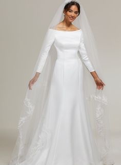 a woman in a white wedding gown and veil posing for the camera with her hands on her hips