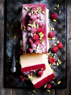 raspberry cheesecake with almonds and pistachio on a black plate