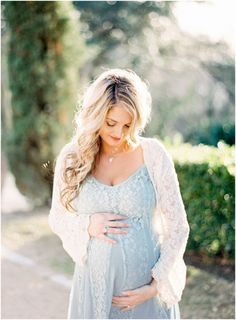 a pregnant woman wearing a blue dress and holding her belly