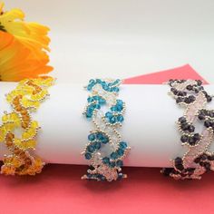 three bracelets are sitting on top of a white napkin with flowers in the background