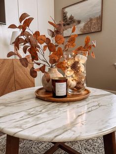 a marble table topped with a vase filled with flowers and candles sitting on top of it