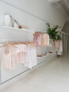 there are many shirts hanging on the rack in this room, and one is pink