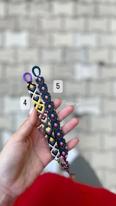 a person holding up a small crocheted object in their hand with numbers on it