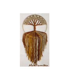 a decorative wall hanging with a tree on it's face and fringes in the shape of a circle