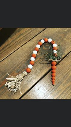 an orange and white beaded necklace with tassels on a wooden table top