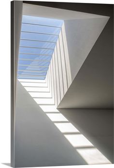 an empty room with white walls and shadows on the floor, as well as a skylight