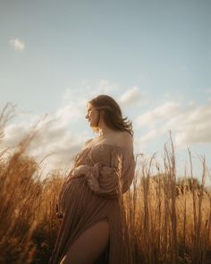 a woman standing in tall grass with her back turned to the camera and looking off into the distance