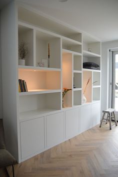 an empty room with white bookcases and wooden floors