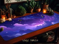 a table with some plants on top of it and a sky scene painted on the surface