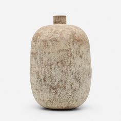 an old stone vase sitting on top of a white surface with a wooden handle in the middle