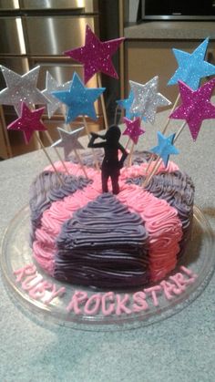 a birthday cake decorated with pink, purple and blue frosting stars on a table