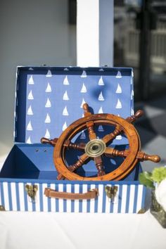 a blue and white box with a wooden steering wheel on the inside sits on a table