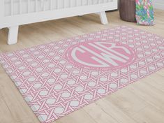 a pink and white monogrammed rug with the letter m on it in front of a crib