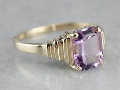 Outstanding! This modern yellow gold setting perfectly frames the amethyst we've set at the center! The tapering stepped yellow gold band looks soft and elegant on the finger, while the rich purple gem glitters with violet sparkles! Metal: 14K Yellow Gold Gem: Amethyst 2.85 Carats Gem Measurements: 7.8 x 9.9 mm, Emerald Cut Ring Size: 10 Marks: "14K UP" Stamped on the inside band Gold Solitaire Amethyst Ring For Formal Occasions, Art Deco Amethyst Ring In Yellow Gold, Yellow Gold Amethyst Ring In Art Deco Style, Art Deco Yellow Gold Amethyst Ring, Modern Yellow Gold Amethyst Ring For Wedding, Modern Yellow Gold Amethyst Wedding Ring, Gold Amethyst Ring With Modern Style, 10 Marks, Purple Gems