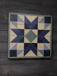 a blue and green patchwork wall hanging on a wooden paneled wall with wood planks