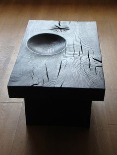 a wooden table with a bowl and spoon on it sitting on a hard wood floor