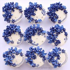 twelve blue and white cupcakes decorated with flowers