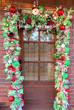 a christmas wreath with ornaments hanging from it's side on a brick wall in front of a window